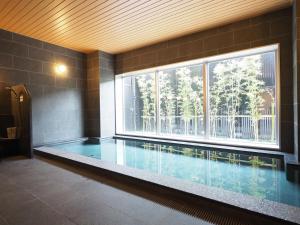 神栖市Tabino Hotel Kashima的一个带大窗户的房间内的游泳池