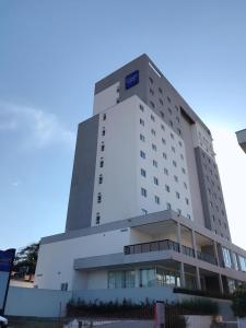 平达莫尼扬加巴Summit Suítes Hotel Pindamonhangaba的一座白色的大建筑,上面有蓝色的标志
