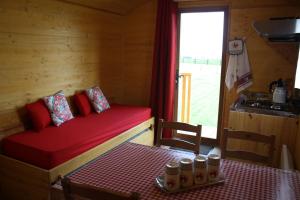 莫尔塔涅欧佩什Roulotte Poulette的小房间设有一张红色的床、一张桌子和一个窗口