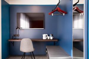 莫尔塞姆Hotel Le Bugatti的蓝色的客房配有书桌和椅子