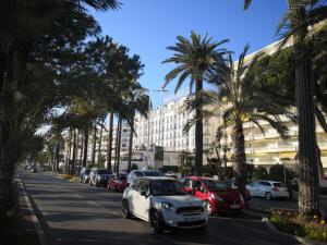 戛纳Apartment Cannes Gallia的一辆白色的汽车沿着棕榈树的街道行驶