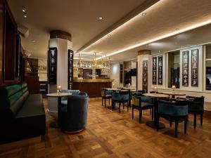 阿姆斯特丹Clayton Hotel Amsterdam American的一间带桌椅的餐厅和一间酒吧