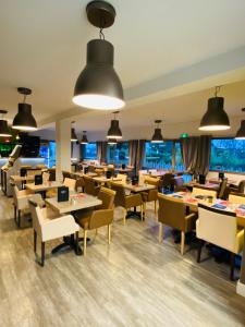 博库泽Atoll Hotel Logis Angers, Beaucouzé的餐厅设有桌椅和窗户。
