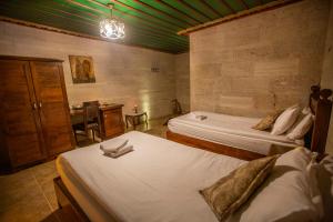 乌奇希萨尔赫尔墨斯窑洞酒店的客房设有两张床、一张桌子和一张桌子
