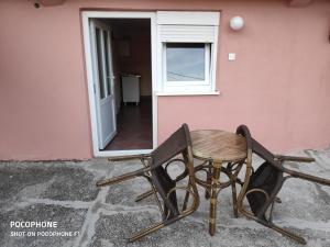 威尔帕扎Apartman Pavle 2的一张桌子和椅子,坐在粉红色房子外面