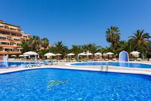 拉克鲁斯巴伊亚普拉亚公寓酒店的度假村的游泳池,配有椅子和遮阳伞