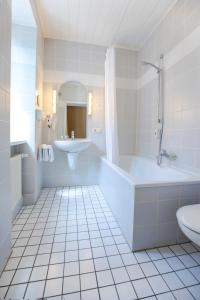 吕德斯海姆哲迈尼尔哈宙斯酒店的白色的浴室设有浴缸和水槽。