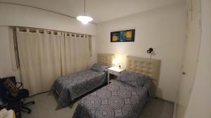 西波列蒂San Martin 900 con estacionamiento的一间卧室配有两张床和一张带台灯的桌子