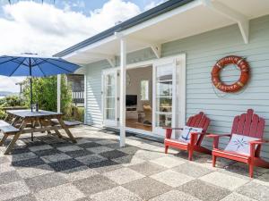 OpuaBlue Peter - Opua Holiday Home的庭院配有桌椅和遮阳伞。