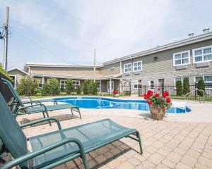 蒙马尼Econo Lodge Inn & Suites的一座建筑前的游泳池,设有两个绿色长椅