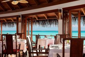 南马累环礁Anantara Dhigu Maldives Resort - Special Offer On Transfer Rates For Summer 2024的一间设有白色桌椅的海洋餐厅