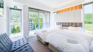二世古默契公寓酒店的一间卧室设有两张床、一张长凳和窗户。