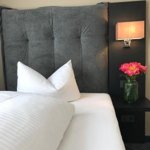 斯图加特罗斯酒店的卧室配有白色的床和花瓶