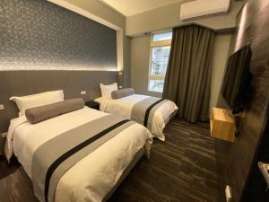 金宁乡雅舍 Arthur Hostel的酒店客房设有两张床和一台平面电视。