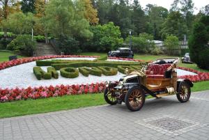 蒙多夫莱班Mondorf Parc Hotel & Spa的停在鲜花花园前的旧车