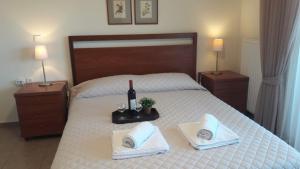 尼亚普拉莫斯Ideal Family House的一间卧室配有一张床、一瓶葡萄酒和毛巾