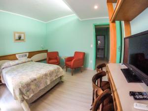 阿雷格里港Milão Hotel的一间卧室配有一张床和一台平面电视