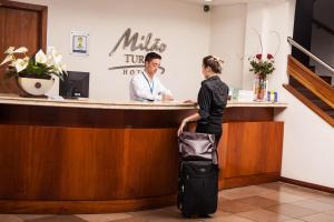 阿雷格里港Milão Hotel的带着行李在现金登记册上等候的女人