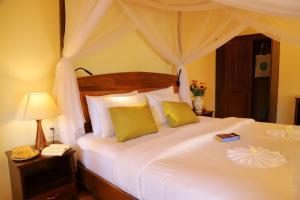 富国槟城侨海滩度假酒店的卧室配有一张带黄色枕头的大型白色床。