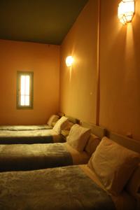 瓦尔扎扎特巴布撒哈拉酒店的带三张床、窗户和灯的房间
