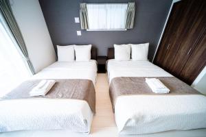 大阪Roof Hanazonocho-Nishi的配有白色床单的酒店客房内的两张床