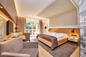 格赖瑙艾姆班德喜酒店的一间卧室配有一张床、一把椅子和一张沙发