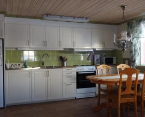 菲奈斯达伦Funäsdalens Stugby的厨房配有白色橱柜和桌椅