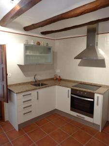 CastelserásCasa Rural El Solanar的厨房配有白色橱柜、水槽和炉灶。