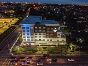 休斯顿Holiday Inn Express & Suites - Houston Westchase - Westheimer, an IHG Hotel的停车场里有很多汽车的大建筑