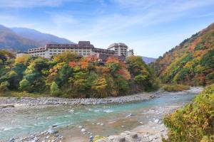 黑部市Kurobe Unazukionsen Yamanoha的河边的山丘上的建筑