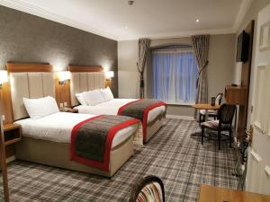 斯莱戈Sligo Southern Hotel & Leisure Centre的酒店客房设有两张床和一张桌子。