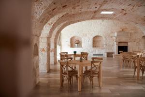奥斯图尼Masseria Grieco的石头建筑中带桌椅的用餐室