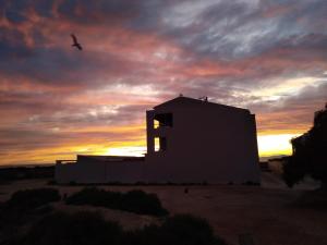 泰拜尔盖Calatabarca B&B的沙漠中的一座建筑,背景是日落