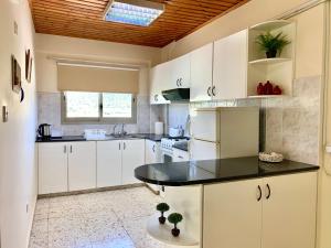 皮斯索里和魔娜斯公寓的厨房配有白色橱柜和黑色台面