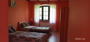 OstrowiceU Magdy的红色的客房设有两张床和窗户。