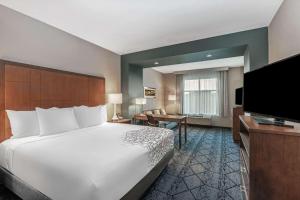 堪萨斯城La Quinta Inn & Suites by Wyndham Kansas City Beacon Hill的配有一张床和一台平面电视的酒店客房