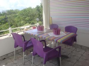 豪特尔ESCALE CREOLE的门廊上的紫色桌子和椅子