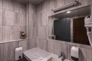 卡赞勒克Семеен хотел Магнолия的一间带水槽的浴室和墙上的电视