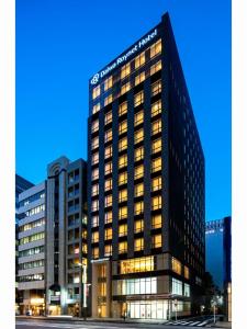 东京Daiwa Roynet Hotel Tokyo Kyobashi PREMIER的一座高大的建筑,晚上有很多窗户