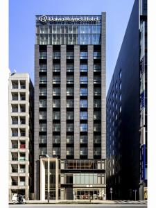 东京Daiwa Roynet Hotel Tokyo Kyobashi PREMIER的一座高大的黑色建筑,上面有标志