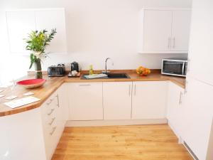 阿尔弗斯顿The Gill Gardens Penthouse, Ulverston - Lake District的白色的厨房配有白色橱柜和木地板