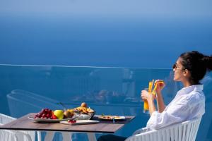 费拉Lilium Hotel Santorini的坐在桌子旁的女人,拿着一碗水果