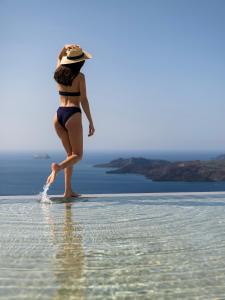费拉Lilium Hotel Santorini的戴帽子的女人站在水里