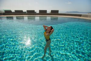 费拉Lilium Hotel Santorini的站在游泳池的水中的女人