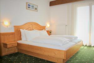 圣卡尼兹亚历克斯酒店的一间卧室配有带白色枕头的木床