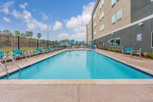 斯普林La Quinta Inn and Suites by Wyndham Houston Spring South的一座带椅子的游泳池以及一座建筑