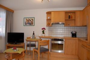 萨斯费Apartment Swiss Chalet的厨房配有木制橱柜和一张桌子及一台电视机