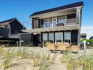 海默特6 person holiday home in Hemmet的海滩上的房子,配有桌椅