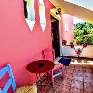 苏卡雷斯Araxovoli Studios - Aραξοβολι Studios的配有桌椅和粉红色墙壁的客房
