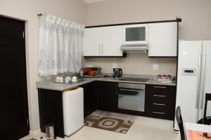 德班莉莉的避风港公寓的厨房配有黑色橱柜和白色冰箱。
